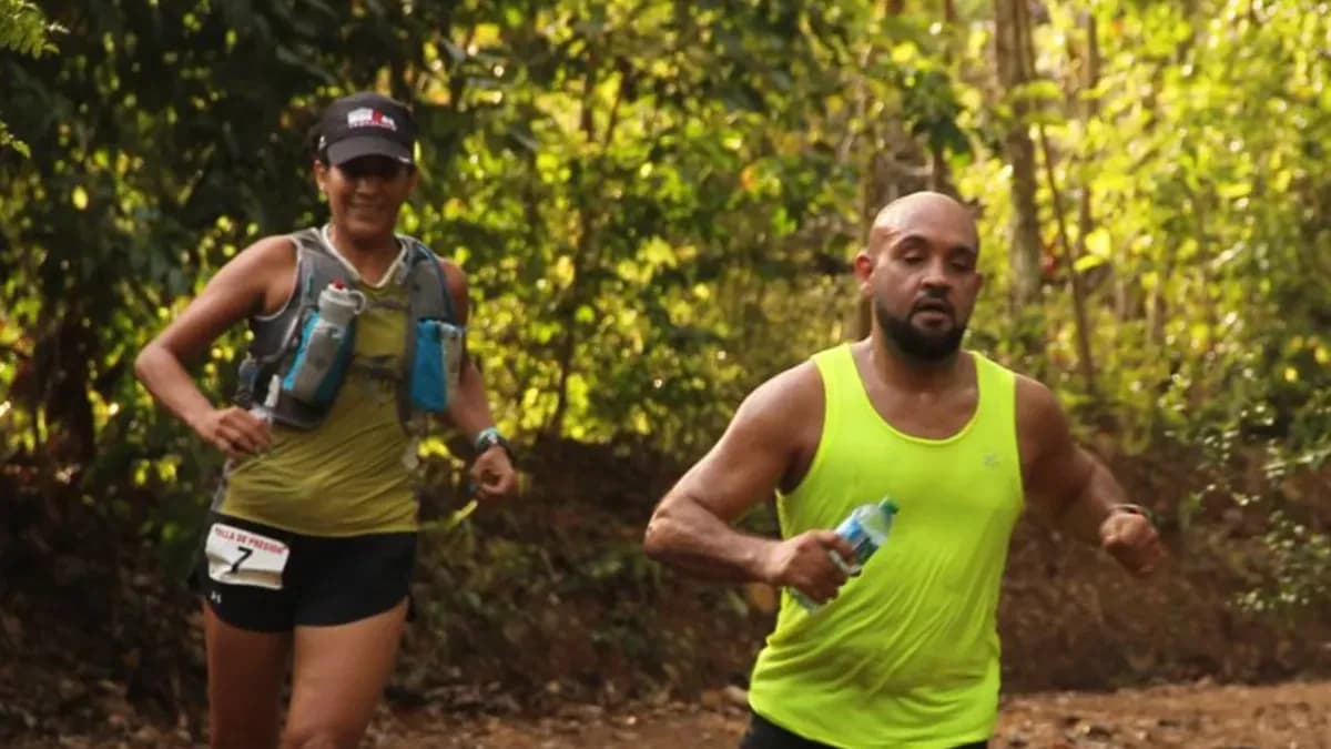 Two runners wearing race bibs on a forest trail during the Pico Duarte Ultra