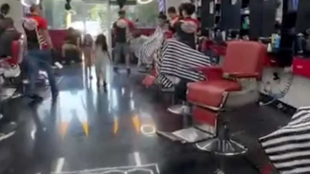 Barberos trabajando en el salón de FinestCutz, con sillas rojas bajo luces LED hexagonales en el techo